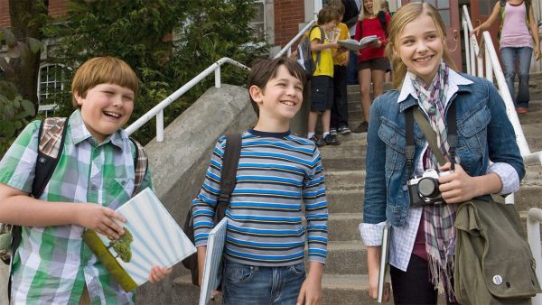 Cast of kids from the 2010 movie Diary of a Wimpy Kid, smiling and joking together, capturing the fun and humor of childhood.