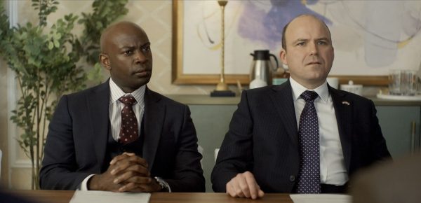 David Gyasi and Rory Kinnear from Netflix’s ‘The Diplomat’ sit at a conference table during a tense meeting scene
